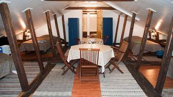 Une pièce mansardée chaleureuse, avec une table ronde et des chaises, des poutres en bois et un plafond en pente.