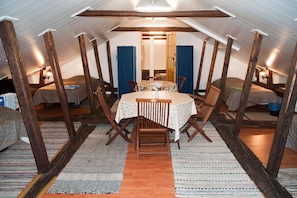 Une pièce mansardée chaleureuse, avec une table ronde et des chaises, des poutres en bois et un plafond en pente.