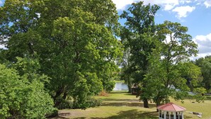 Un parc avec un kiosque, des arbres et un étang.
