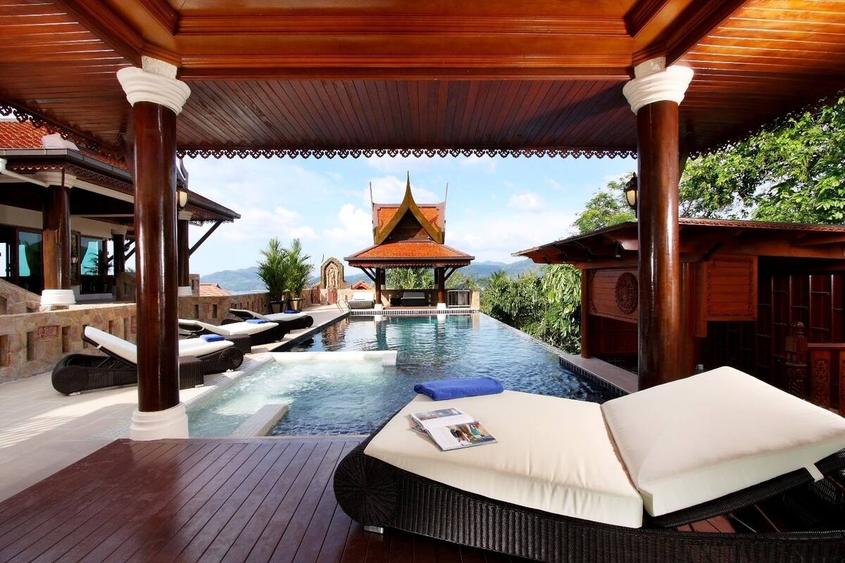 A luxurious outdoor pool area with lounge chairs and a view of a traditional building in the background.