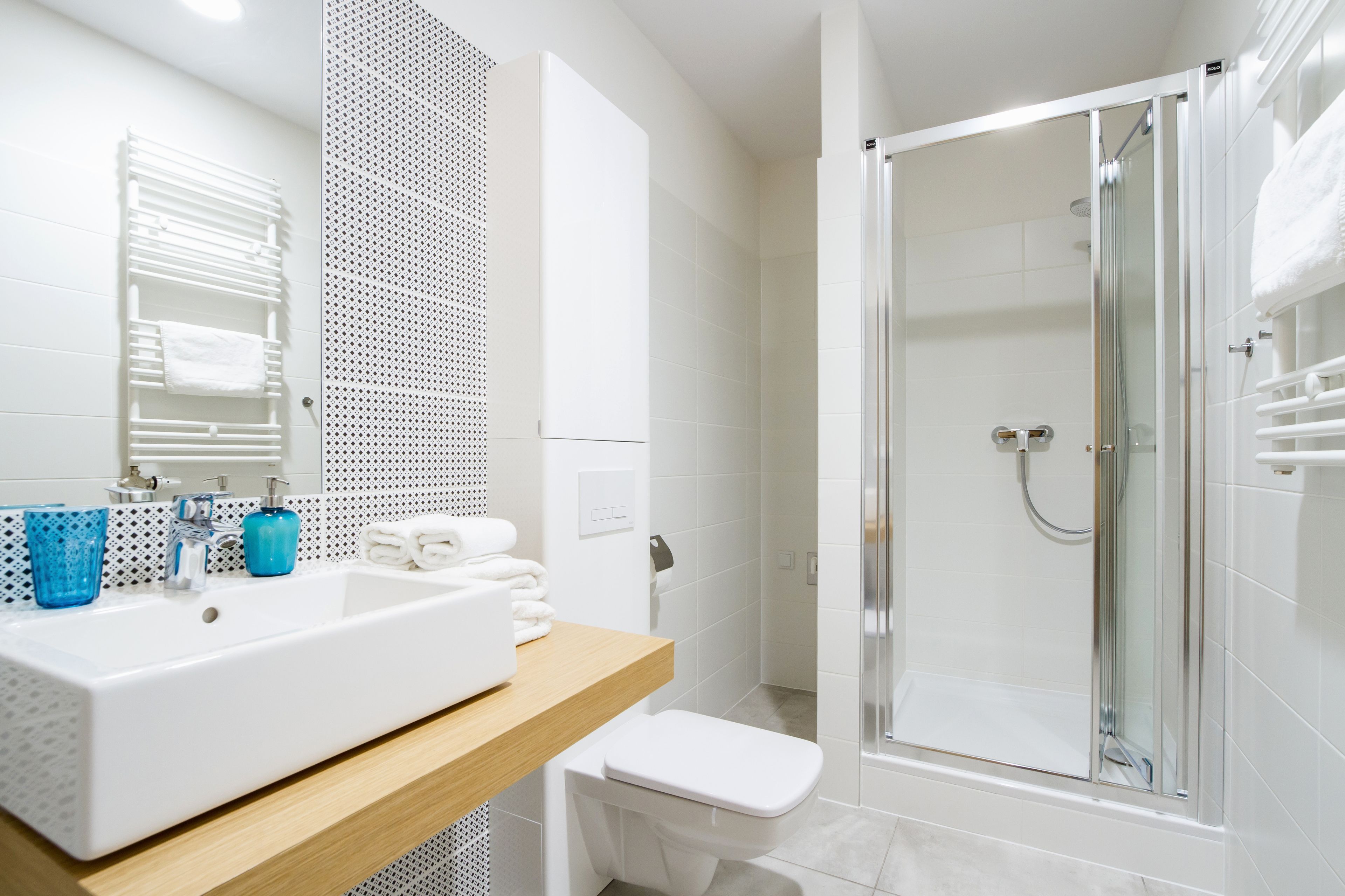 A modern bathroom with a large white sink, a toilet, and a glass-enclosed shower.