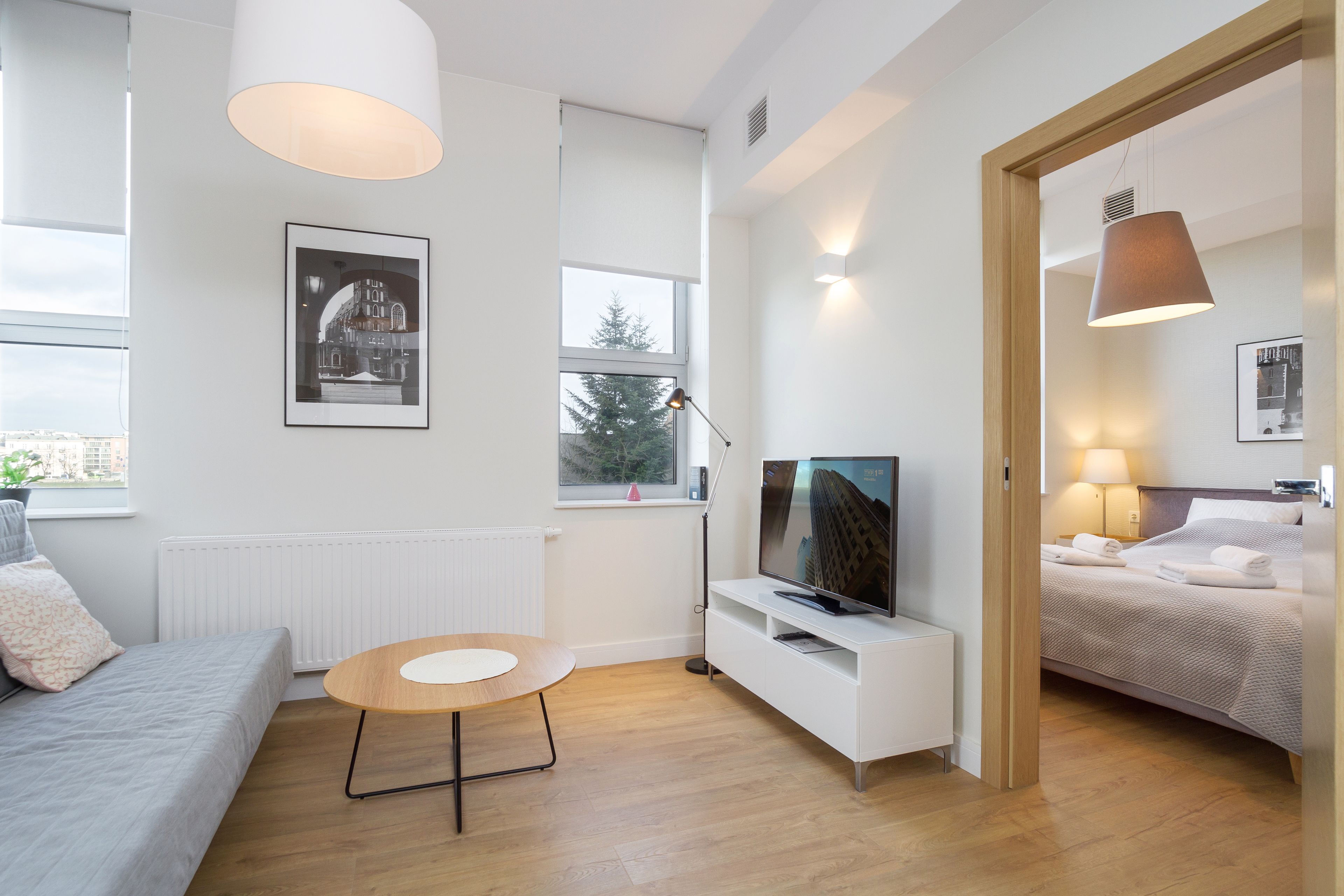 Una habitación moderna y luminosa con sofá, una mesa redonda, televisor y cama.