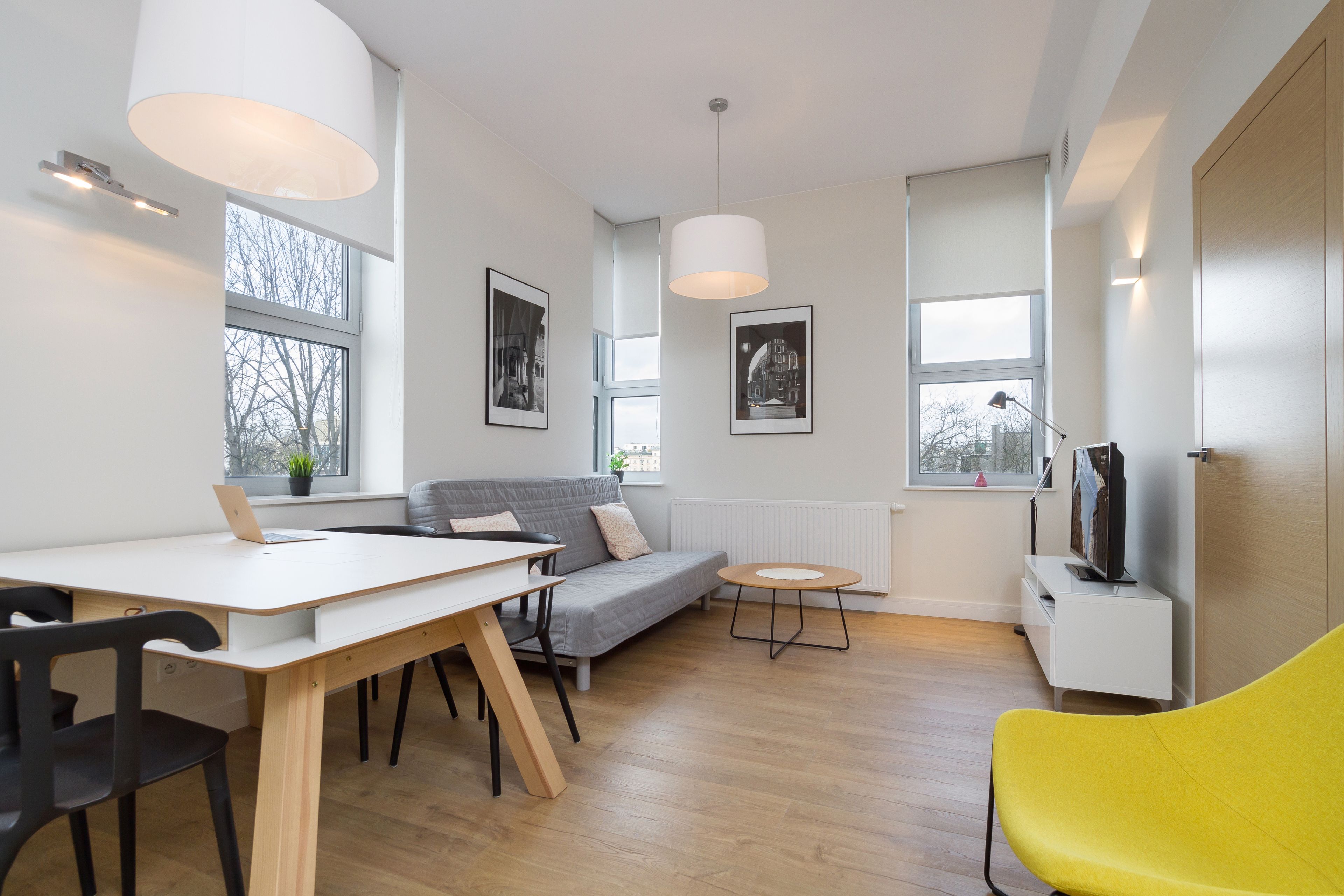 A modern living room with a dining table, sofa, and yellow chair.