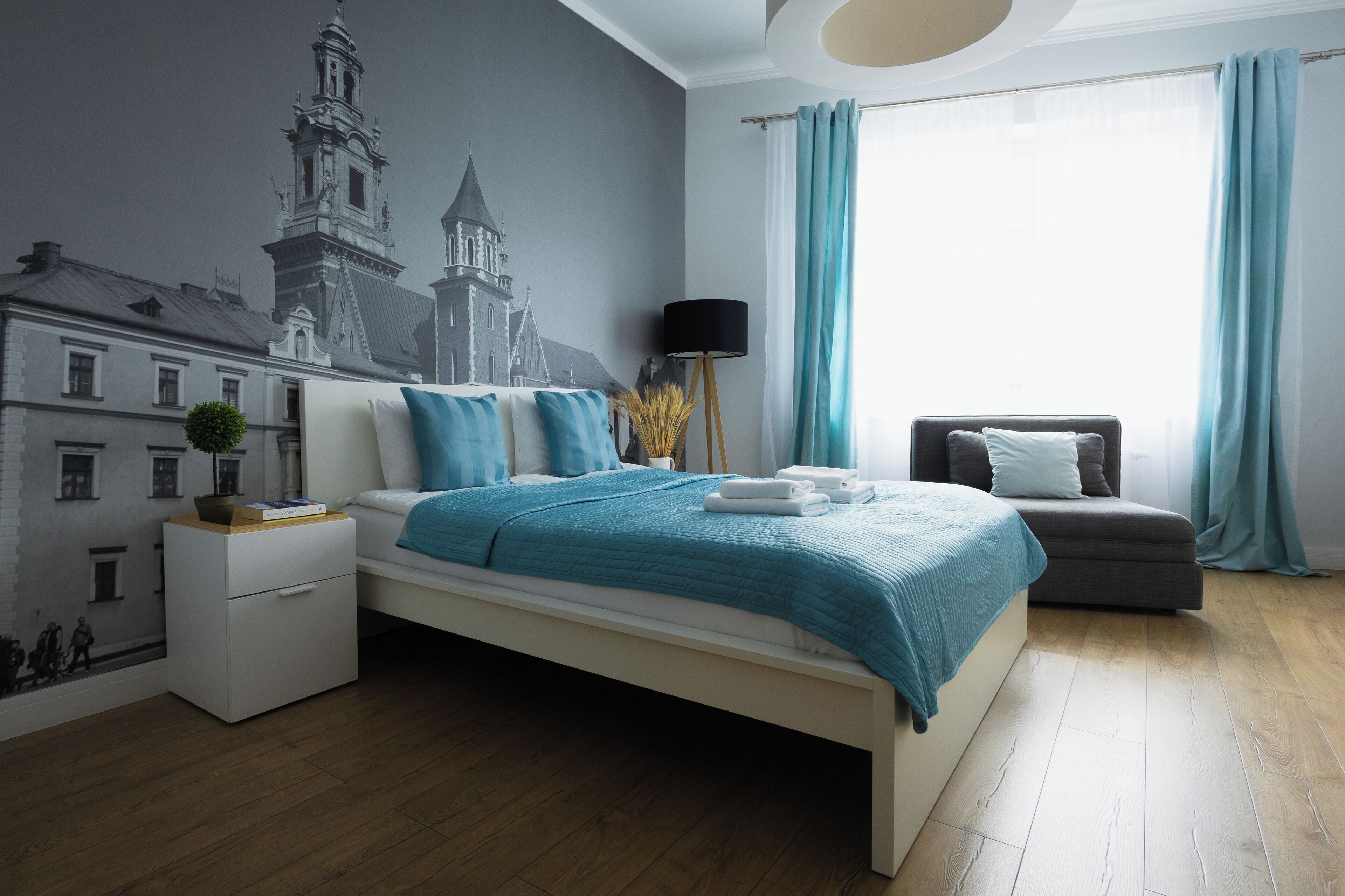 Een moderne slaapkamer met een bed, nachtkastje, lamp en een stoel.