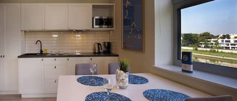 A modern kitchen with white cabinets, a microwave, and a dining area with a table set for two.
