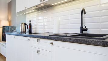 Een moderne keuken met witte kastjes, een zwarte kraan en een magnetron boven de gootsteen.