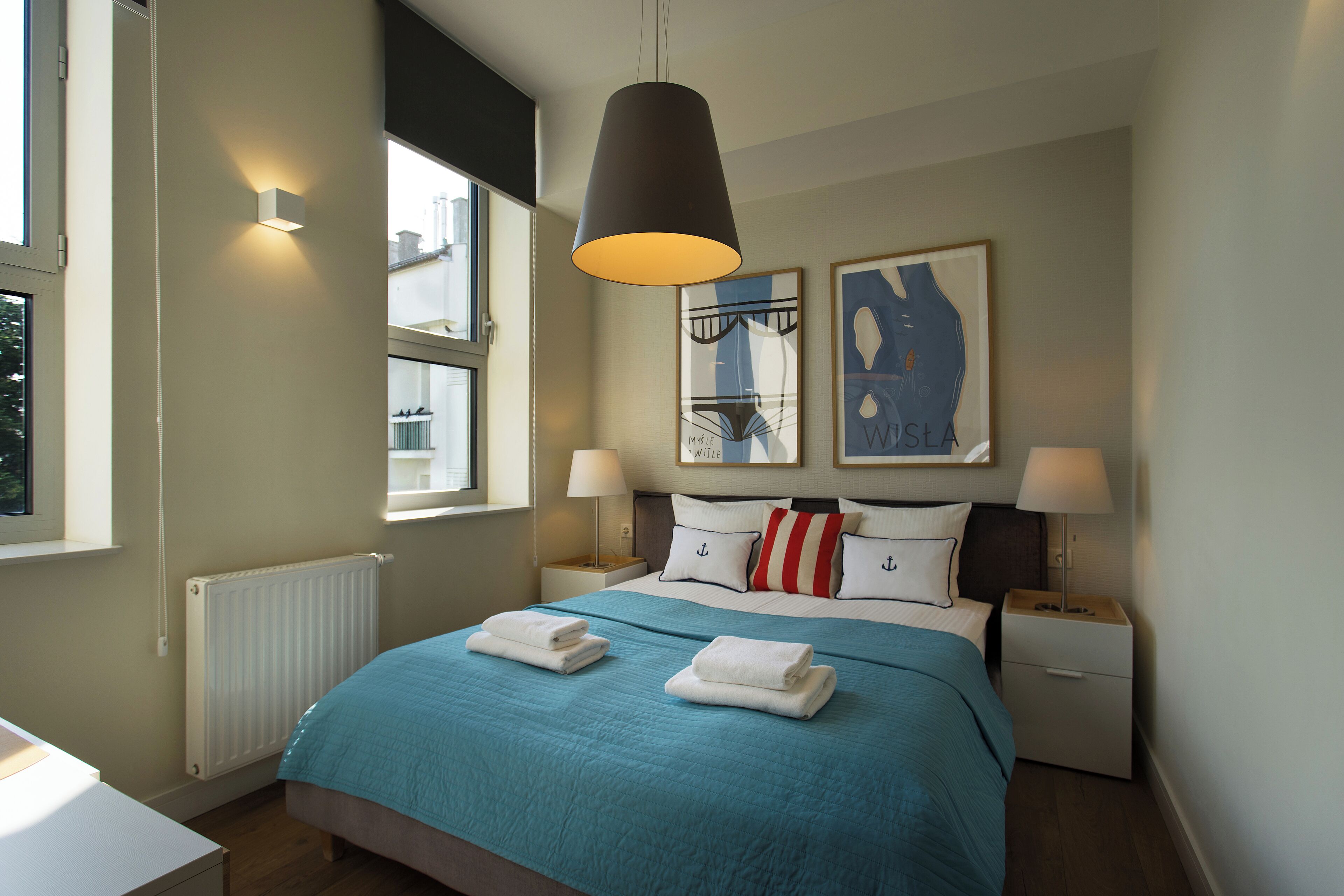 A modern hotel room with a large bed, two bedside tables, a window, and artwork on the wall.