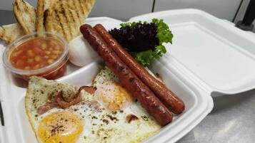 Un repas composé d’œufs, de saucisses, de pain grillé et d’une salade, le tout servi sur un plateau blanc.