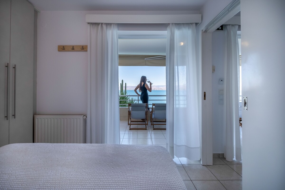 Un dormitorio con una cama grande, vistas al balcón y un vistazo al mar.