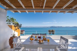 Une table dressée avec de la nourriture et des boissons sur un balcon donnant sur la mer.