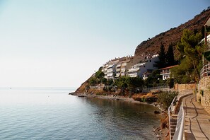 Une ville côtière avec des bâtiments construits à flanc de colline, une promenade pavée le long de la côte et une vue dégagée sur la mer.