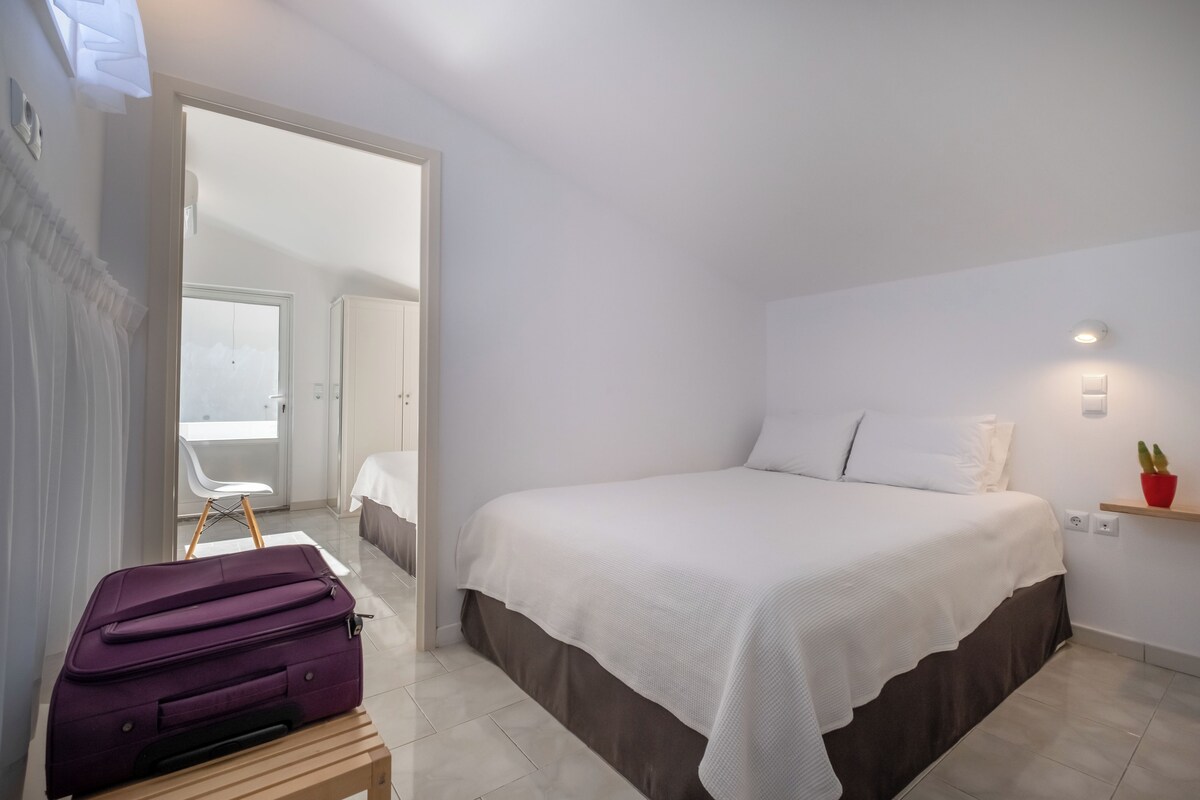 Ein Schlafzimmer mit einem Bett, einem Koffer, einem Sessel und einem kleinen Tisch.