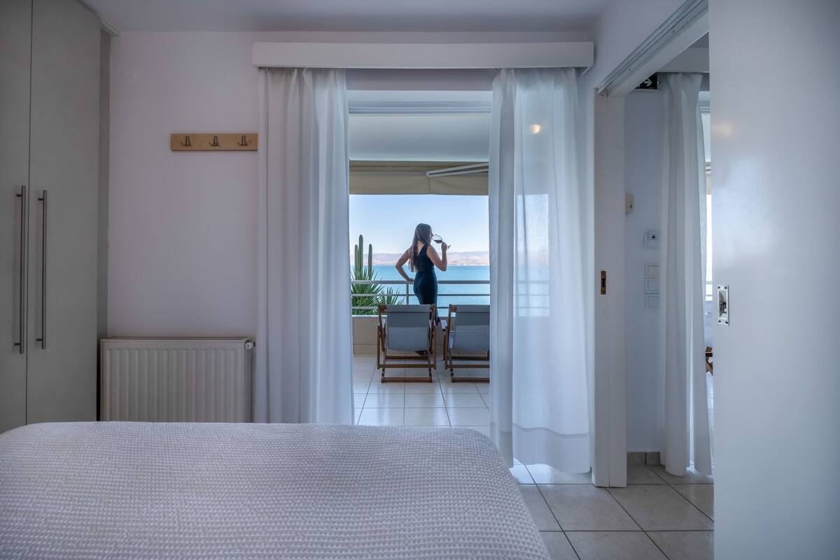 Un dormitorio con una cama grande, vistas al balcón y un vistazo al mar.