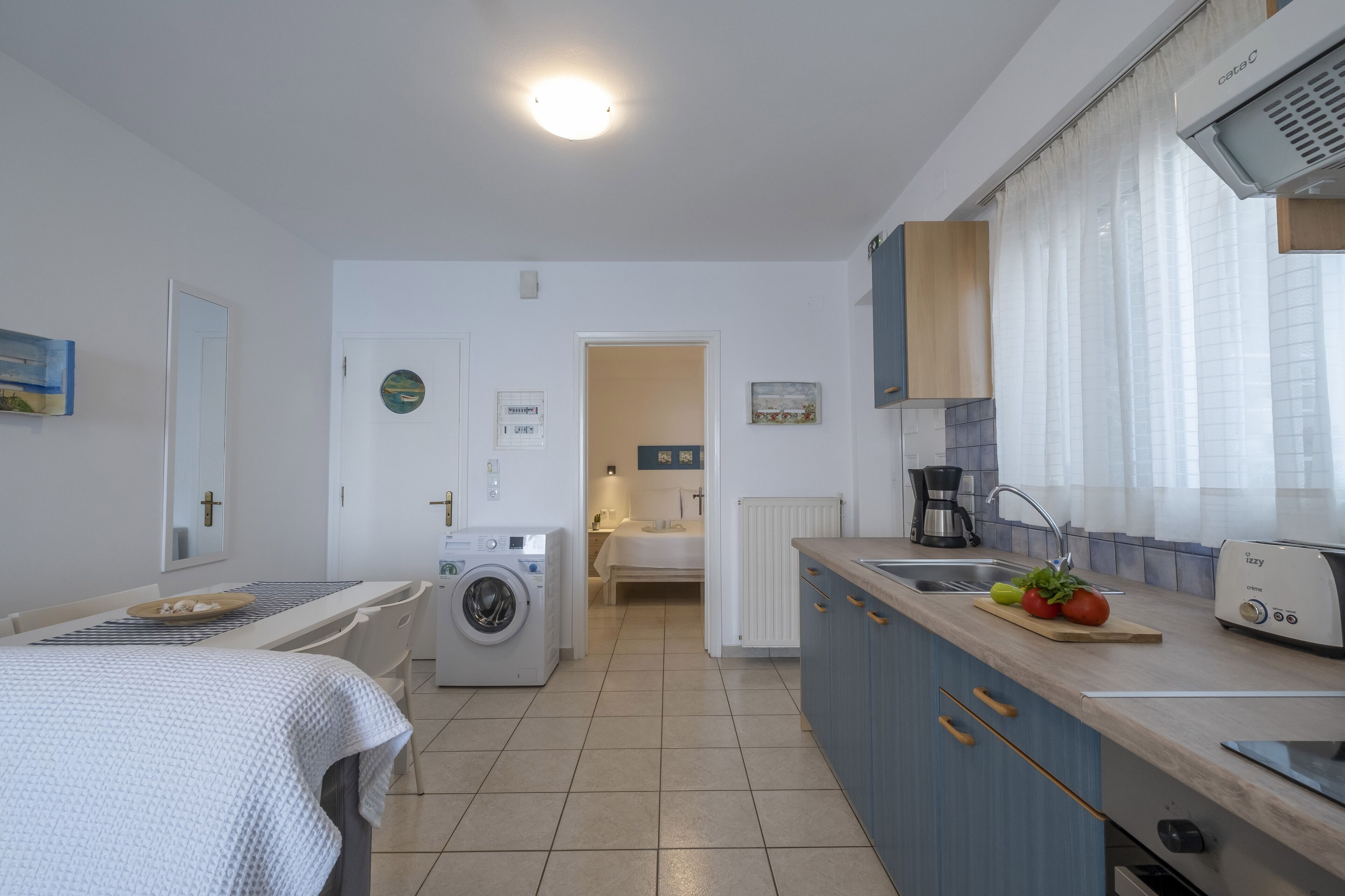 Una cucina compatta con lavatrice, un letto e un'area pranzo.