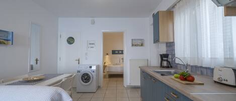 Una cucina compatta con lavatrice, un letto e un'area pranzo.