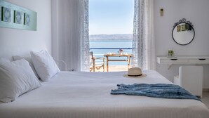 Un dormitorio con cama, escritorio y vista al mar.