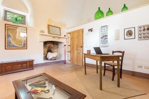 A living room with a fireplace, a dining table with chairs, a glass coffee table, and various wall decorations.