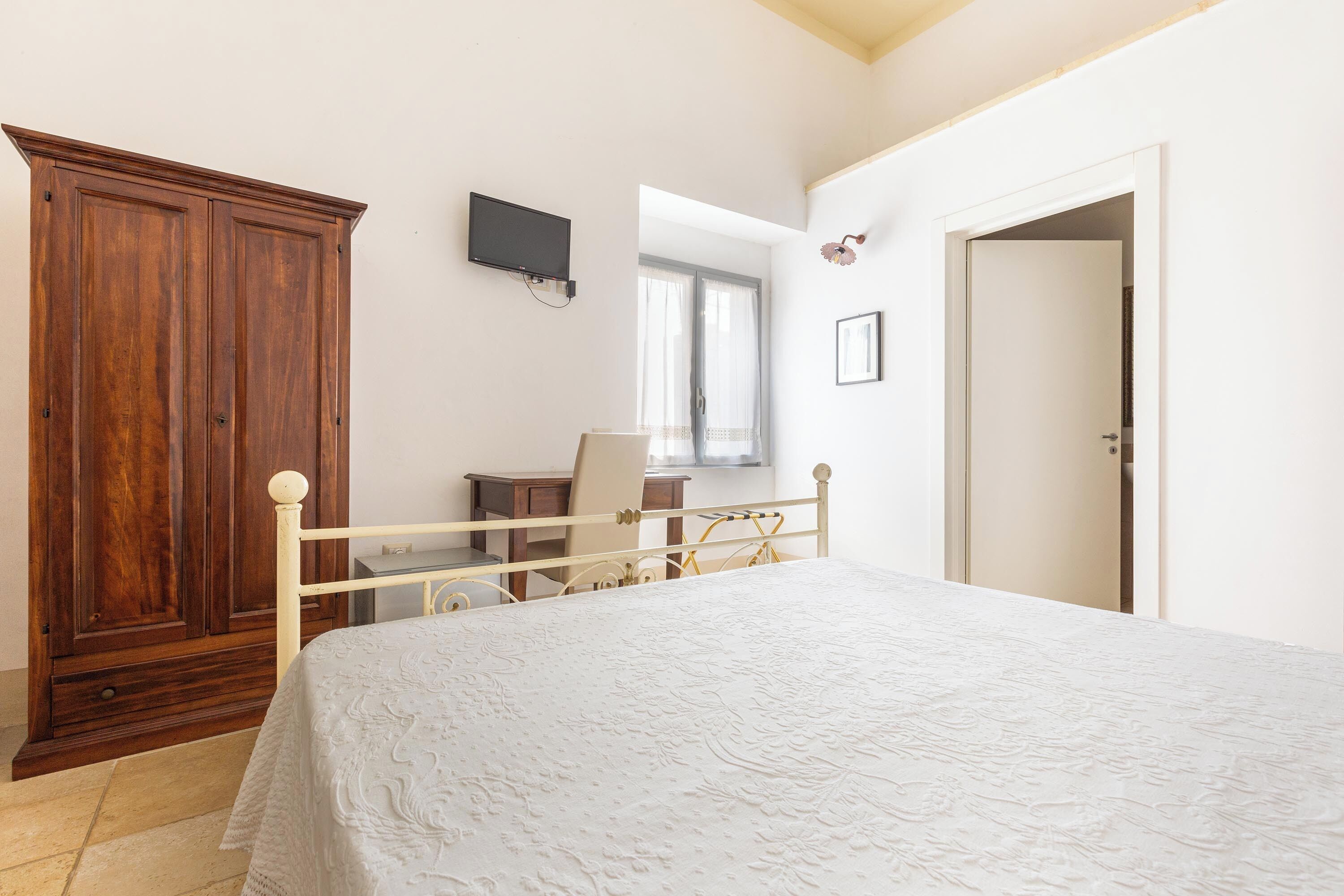 Une chambre à coucher comprenant un lit, une armoire, un bureau et un téléviseur.