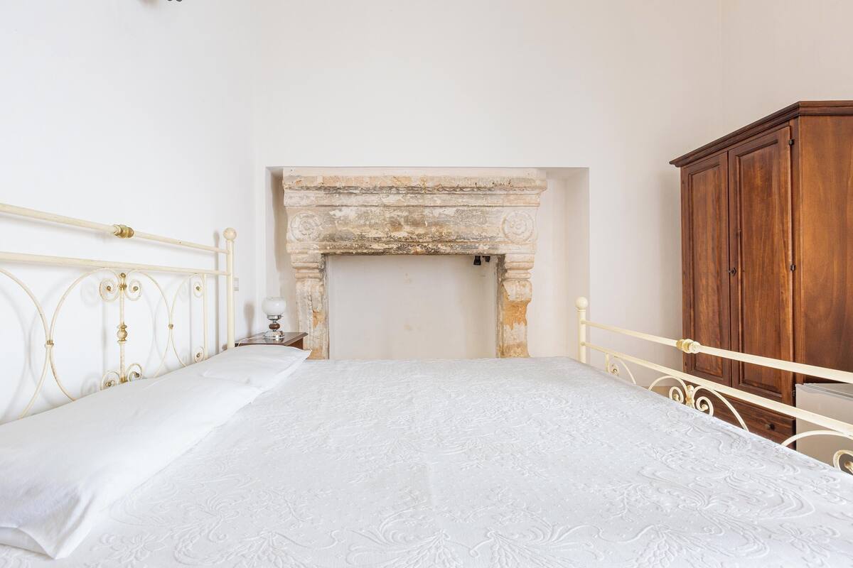 Ein Schlafzimmer mit einem Bett, einem Holzschrank und einem Kamin.