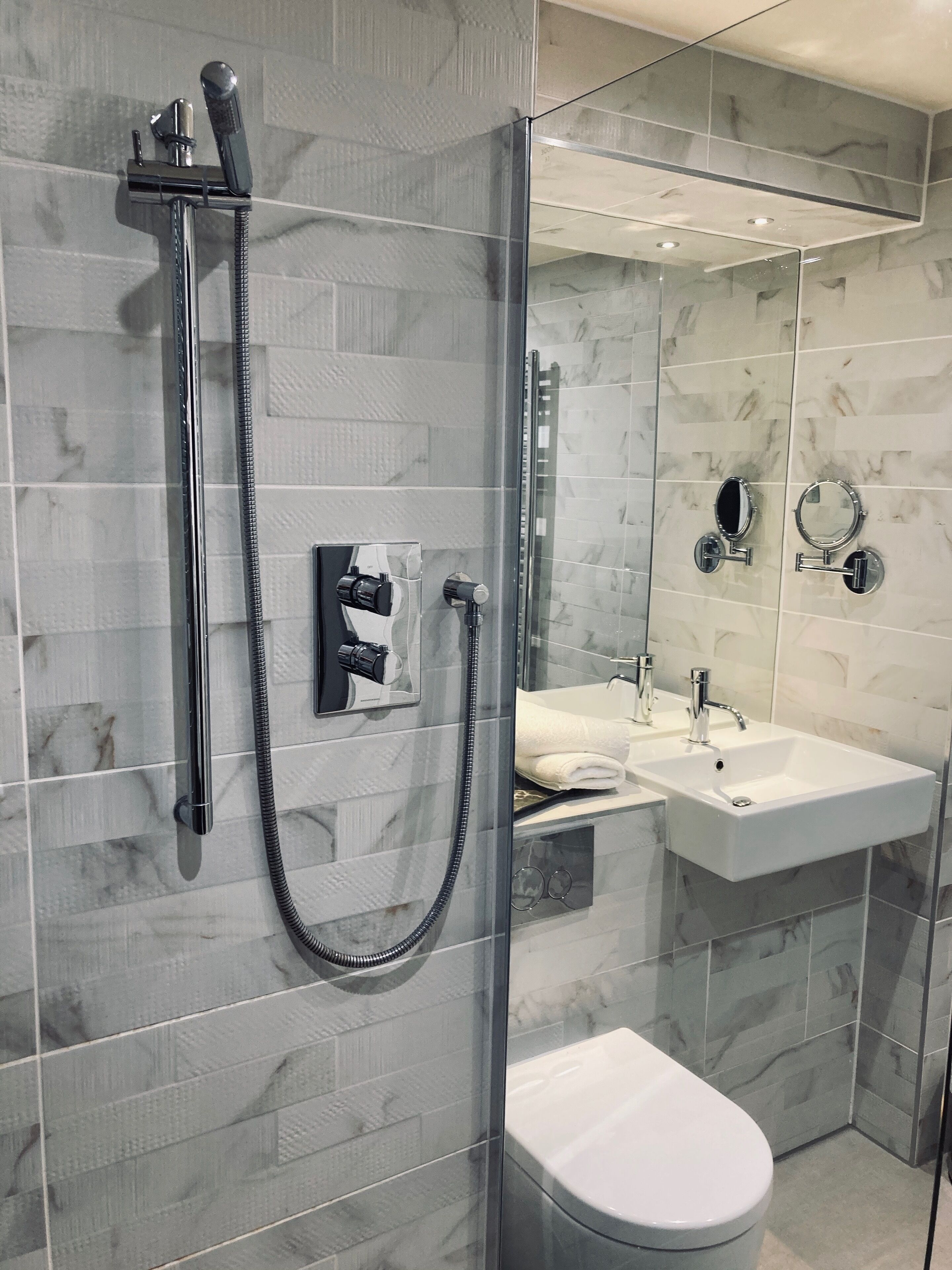 A modern bathroom with a glass-enclosed shower, a white toilet, and a vanity with a mirror and sink.