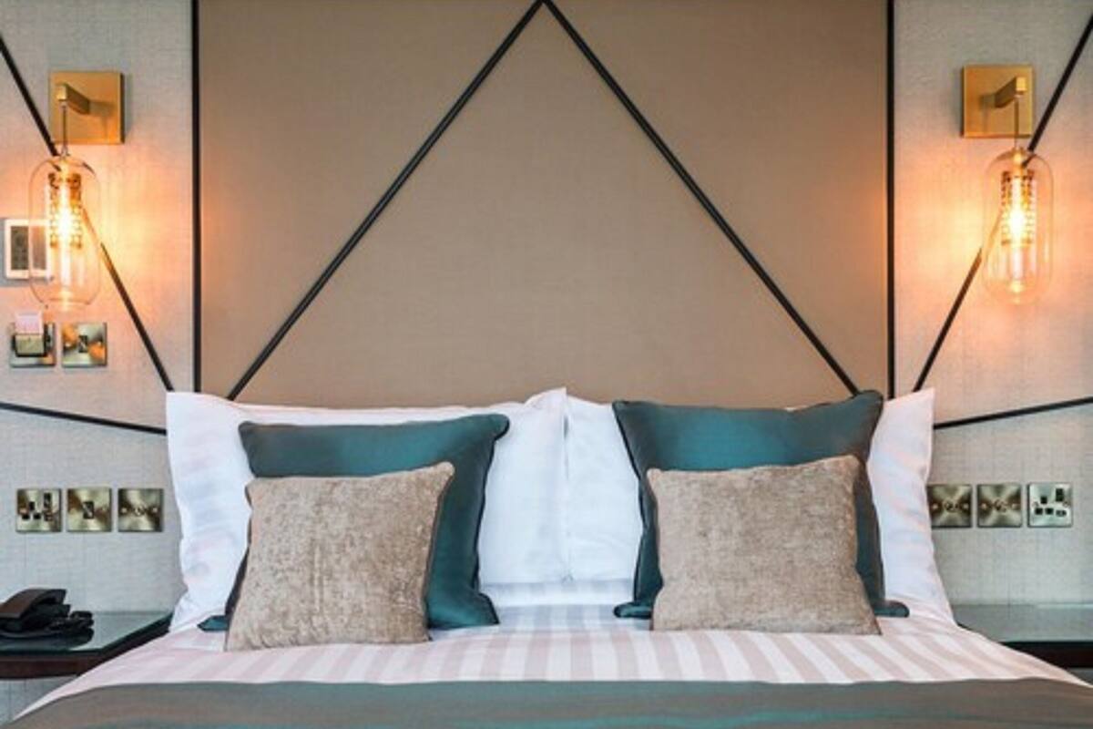 A hotel room with a bed, two bedside lamps, and a wall-mounted phone.