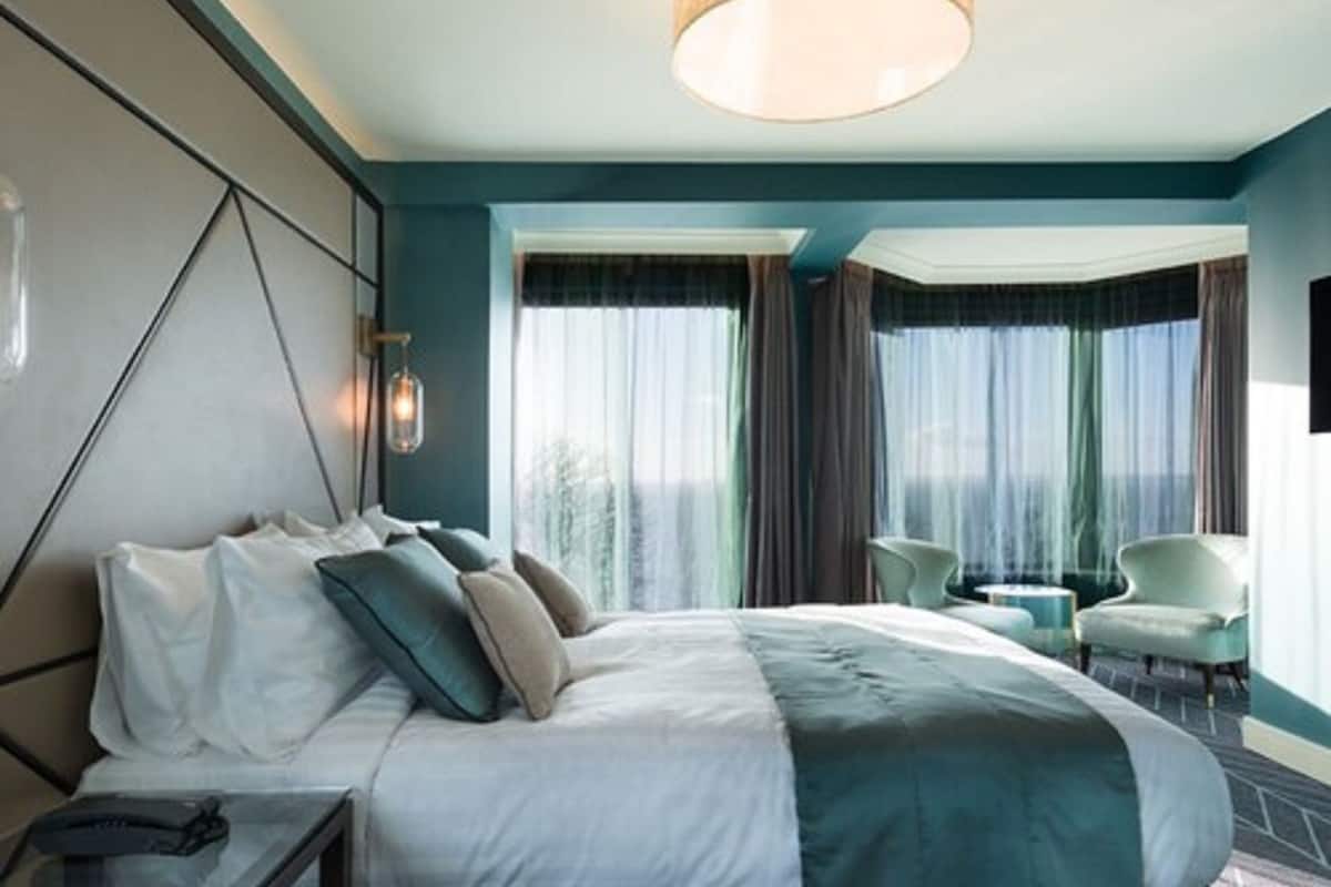 A modern hotel room with a large bed, a desk, and two chairs.