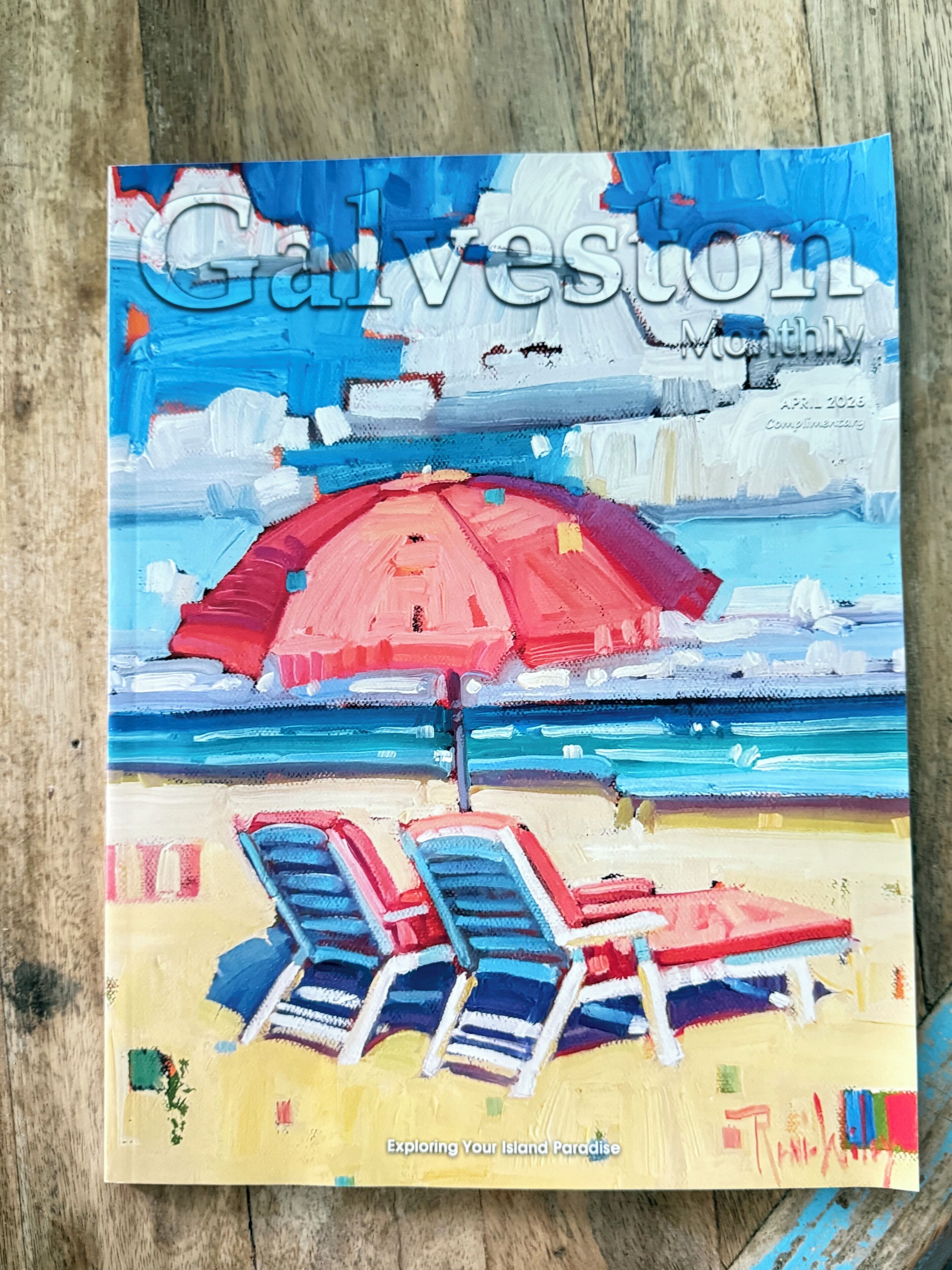 Eine Magazineinband mit dem Titel 'Galveston Monthly', zeigt eine Strandansicht, inklusive eines roten Sonnenschirms und Liegestühlen.