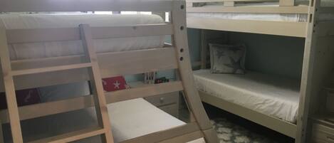 A bunk bed room with a window, a desk, and a patterned rug.