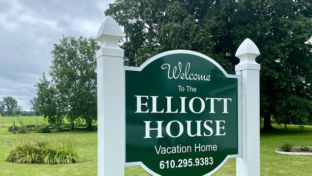 A welcome sign for the Elliott House, a vacation home, with a contact number.