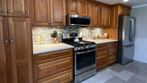 A modern kitchen with wooden cabinets, stainless steel appliances, and a tiled backsplash.