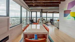 Un espace de bureau moderne doté d’une grande table, de plusieurs chaises et offrant une vue sur la ville grâce à de larges fenêtres.