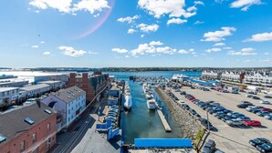 Un port de plaisance avec des bateaux amarrés, un parking et des bâtiments le long du front de mer.