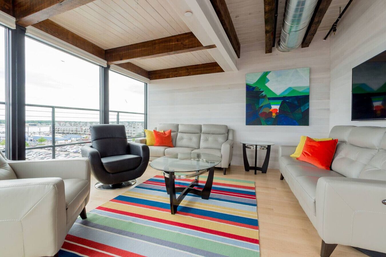 Un salon moderne avec une grande fenêtre, un canapé, un fauteuil et une table basse.