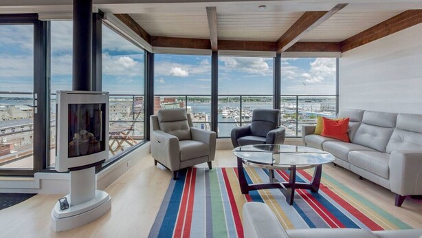 Un salon spacieux doté d’une grande fenêtre, d’une cheminée et offrant une vue sur un port de plaisance.
