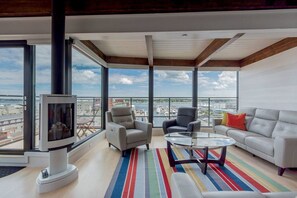 Un salon spacieux doté d’une grande fenêtre, d’une cheminée et offrant une vue sur un port de plaisance.