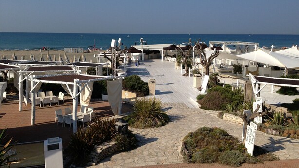 A beachside resort with outdoor seating, umbrellas, and a view of the sea. - Private flat in Rome Ostia Antica (Ostia Antica, Roma)