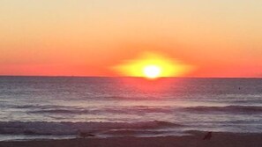 Un coucher de soleil sur l’océan, avec des vagues.