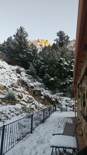 A snow-covered outdoor area with a stone building, a metal fence, and a wooden bench. - August Just Opened Up & Beautifully Wild has A/C! 21-Z3031 (Bellvue)