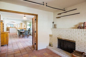 A spacious living area with a fireplace, a kitchen in the background, and a dining area. - Beautiful Hacienda with Pool and Mountain Views (la quinta)