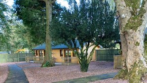 A wooden cabin with a sloped roof, surrounded by a gravel path and a wooden fence. - Shieldhill Castle Hotel (Biggar)