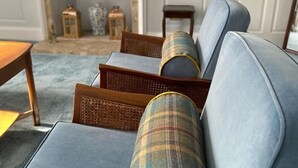 A seating area with a sofa and chairs, a fireplace, and a mirror above it. - Shieldhill Castle Hotel (Biggar)