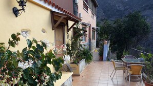 Une terrasse avec des meubles d’extérieur, un sol carrelé et des plantes en pot.