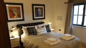 Un letto rifatto con un copriletto color beige e cuscini, una lampada da comodino e un quadro incorniciato sopra.