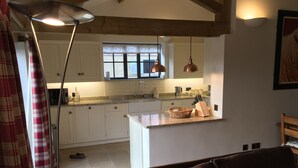 Una cucina moderna con mobili bianchi, un piano di lavoro in granito e lampade a sospensione in rame.