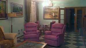 Un salon avec deux fauteuils violets, une table basse et un tableau accroché au mur.