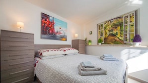 Un dormitorio con cama, cómoda, ventana con vistas y un cuadro en la pared.