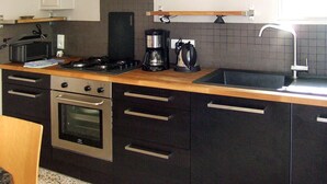 Una cocina moderna con estufa, horno, cafetera y pileta.