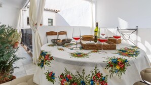 A dining area with a table set for two, featuring a floral tablecloth, two wicker baskets, and two wine glasses with red wine. - IN OFFER - LUXURY HOUSE WITH TERRACE IN LA JUDERIA, PAX 10 (SEVILLA)