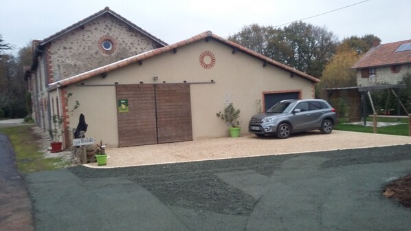 A building with a large garage door, a parked SUV, and a potted plant in front.