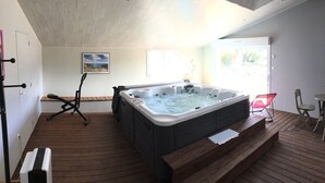 A spacious room with a hot tub, wooden flooring, a ceiling fan, and a painting on the wall. - Gîte with Jacuzzi in the countryside 18 kms from the ocean (La Boissière-Des-Landes)